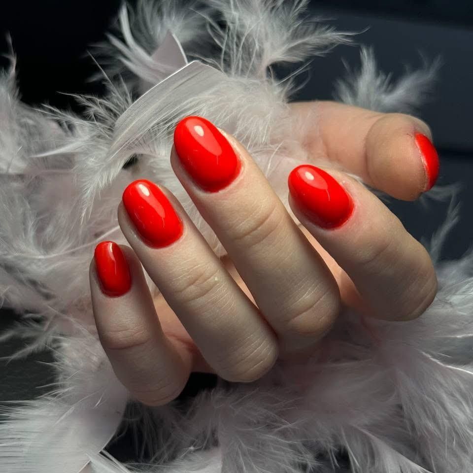 Dłoń z paznokciami w intensywnym czerwonym kolorze o wysokim połysku, prezentująca elegancki i klasyczny manicure
