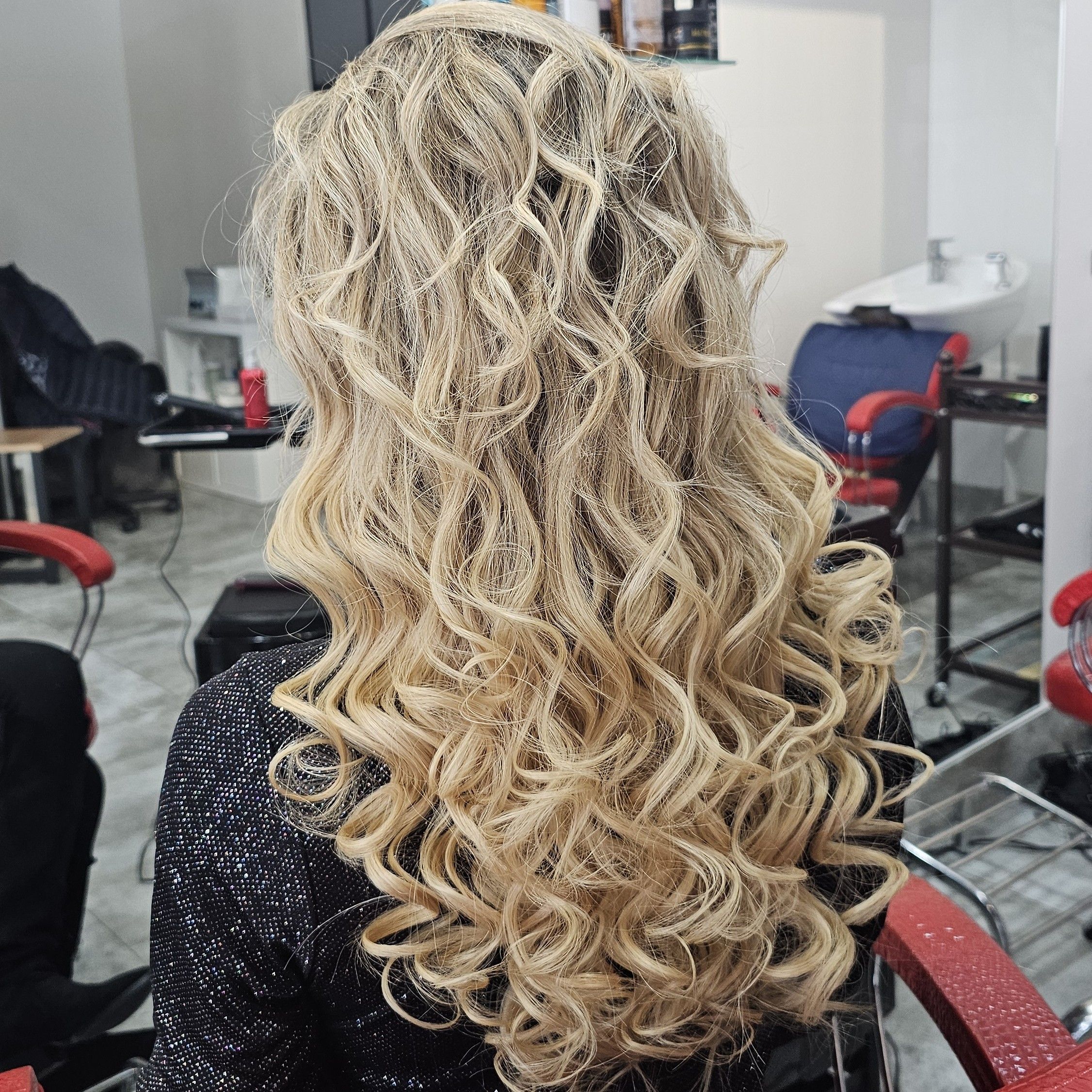 Długie włosy blond ułożone w wyraźne, sprężyste loki, nadające fryzurze objętość i efektowny, elegancki wygląd